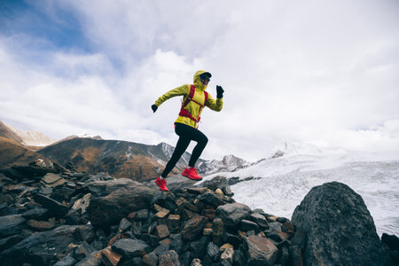 Woman trail runner cross country running up to winter snow mountain topの写真素材