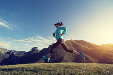 Young woman runner running at mountain topの写真素材