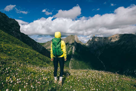 Successful woman backpacker hiking on alpine mountain peakの写真素材
