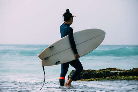 Woman surfer with surfboard going to surf the big wavesの写真素材