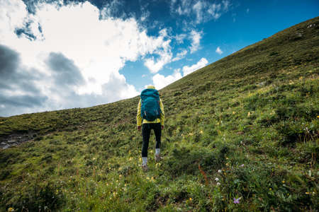 Successful woman backpacker hiking on alpine mountain peakの写真素材