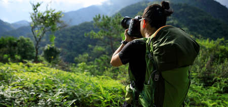 Woman photographer taking pictures in summer mountainsの写真素材