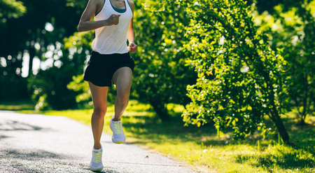 Fitness woman running on sunny tropical park trailの写真素材