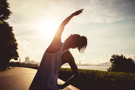 Fitness woman warming up on sunny tropical seasideの写真素材