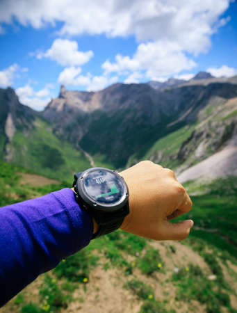 Hiker on high altitude mountain top checking the altimeter on the sports watchの写真素材