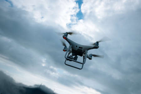 White drone with camera flying in summer mountain topの写真素材