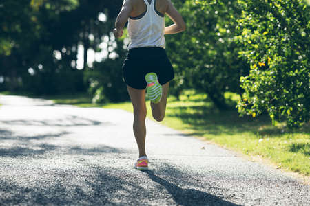 Fitness woman running on sunny tropical park trailの写真素材