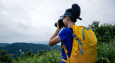 Woman photographer taking pictures in summer mountainsの写真素材