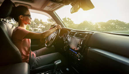 Woman driving car on sunrise mountain roadの写真素材
