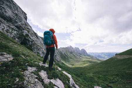 Successful woman hiking on sunset alpine mountain peakの写真素材