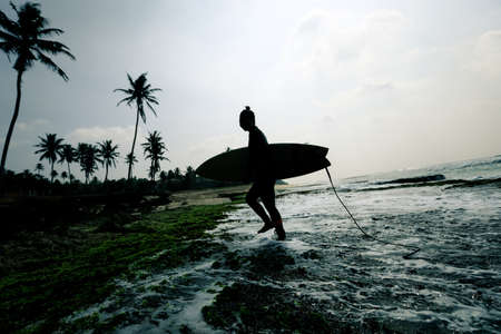 Woman surfer with surfboard going to surf the big wavesの写真素材