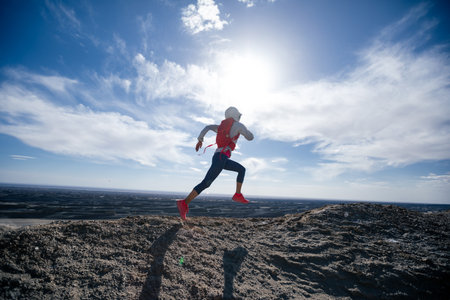 Woman trail runner cross country running on sand desert mountain topの写真素材