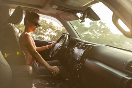 Woman driving car on sunrise mountain roadの写真素材