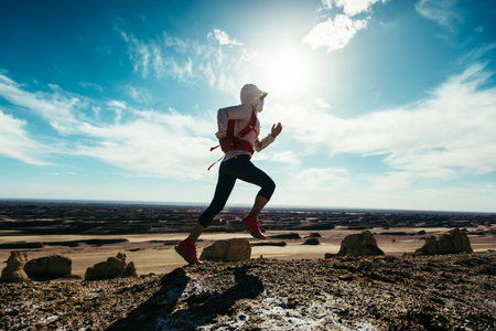 Woman trail runner cross country running on sand desert mountain topの写真素材