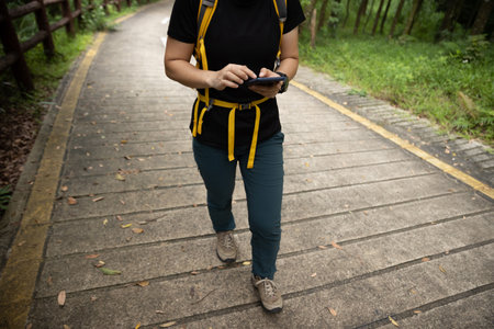 Woman hiker using smartphone on forest trailの写真素材
