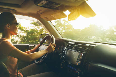 Woman driving car on sunrise mountain roadの写真素材