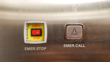 Emergency stop button on the stainless steel elevator cabin, closeup of photo