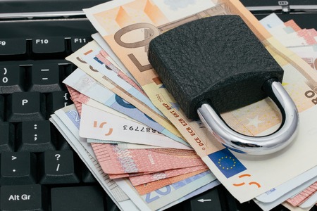 Padlock on a layer of money on a PC keyboardの写真素材