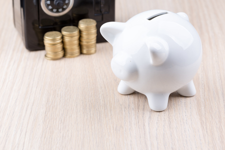 White piggy bank with black metal coin bank in background: a concept for either withdrawing or depositing moneyの写真素材