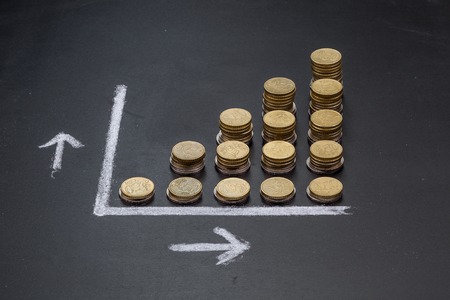 A graph on a clean black board made up with coins showing growthの写真素材