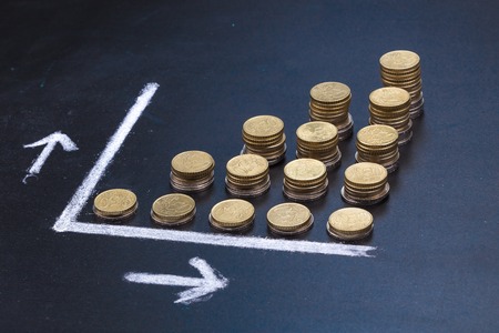 A graph on a clean black board made up with coins showing growthの写真素材