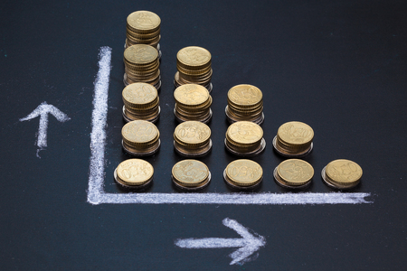 Blackboard showing  a graph with coins portaying a decrease or a lossの写真素材