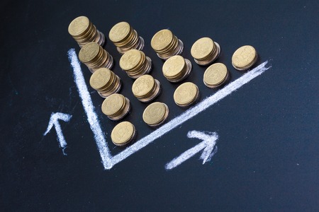 Blackboard showing  a graph with coins portaying a decrease or a lossの写真素材