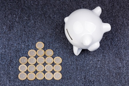 White piggy bank on dark background: saving for a house, coins in the shape of a houseの写真素材