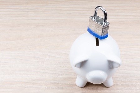 Piggy bank with padlock on wooden tableの写真素材