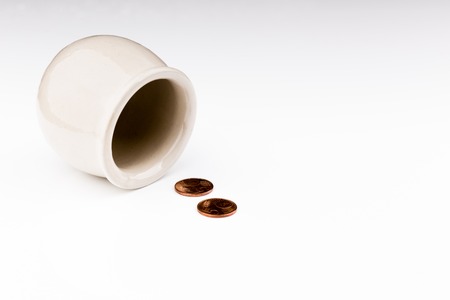 A pot on its side with a few coins, a concept of a tight budgetの写真素材