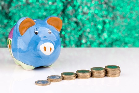Blue piggy bank with a stack of coins and a green backgroundの写真素材