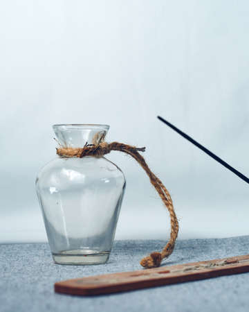 Glass jar with a rope around it and incense stick with censer