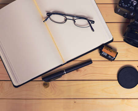 Preparation of a session with an old camera, film and a pen on an open notebookの写真素材