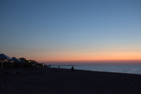 Silhouette of a lonely man sitting on the beach and watching the sunset. Sea of Azov. Krasnodar...