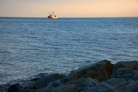 The ship against the background of pink clouds at sunset sails on the waves. summer evening....