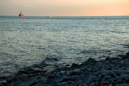 The ship against the background of pink clouds at sunset sails on the waves. summer evening....