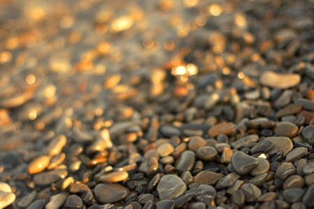 A transparent sea wave rolls onto a pebble beach, the concept of rest and travel, tranquility and reflection on a warm summer day, defocusing, blurred background, selective focus, bokeh.の写真素材