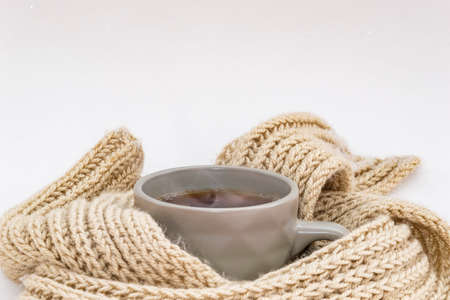 Mug of tea with steam in a knitted scarf.の写真素材