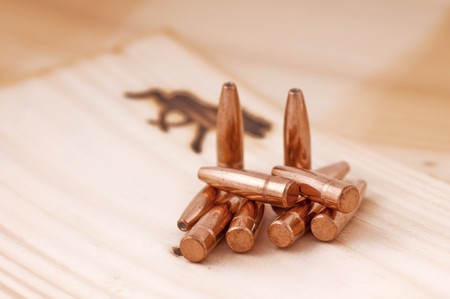 Bullets lying and standing on a wooden surface.の写真素材