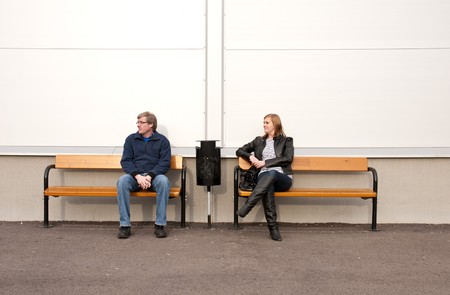 Man and woman sitting on bench waiting for something.の写真素材