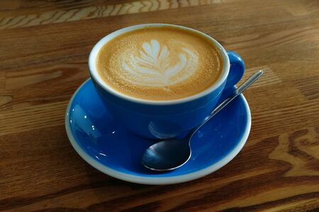 a blue cup of coffee with a spoon is on the tableの写真素材