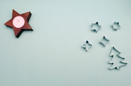 metal cookie cutters Christmas tree and stars, wooden candlestick with a candle on a blue background copy spaceの写真素材