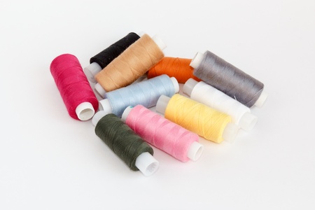 Multy coloured bobbins of thread on white background