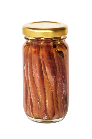 Anchovy fillets in oil in a transparent glass jar closed with a yellow lid. Full jar of salty anchovy fillets isolated on white background close up.の写真素材