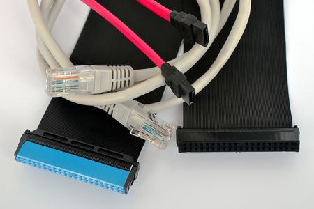Computer cables of black, pink and gray colors picturesquely lie on a white background, close up,...