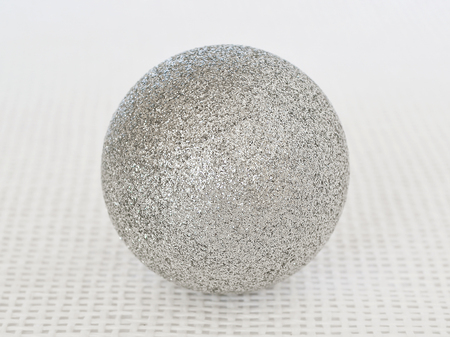 One shiny silver christmas ball with sparkles on a white textural background close upの写真素材