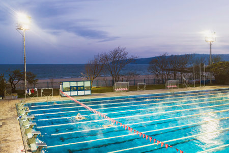 Varna, Bulgaria, November 2018. Swimming complex Primorsky on the Black Sea coast. Outdoor sport swimming pool lit by powerful spotlights on a dark autumn evening sky backgroundのeditorial素材