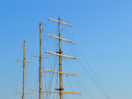 Three masts of a sailing ship with folded up sails and shrouds against a blue summer sky, copy spaceの写真素材