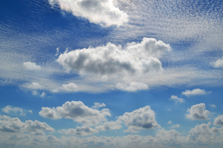 A lot of white clouds of different types: cumulus, cirrus, layered high in blue sky on a sunny day