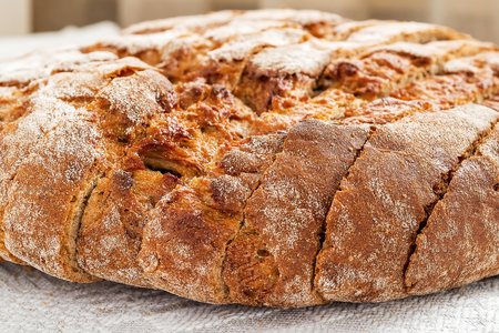 Sliced round loaf of rye bread with an appetizing crispy brown crust on a gray linen tablecloth....